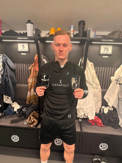 Fotbollsspelare i omklädningsrummet håller upp sina personliga benskydd från Adelante