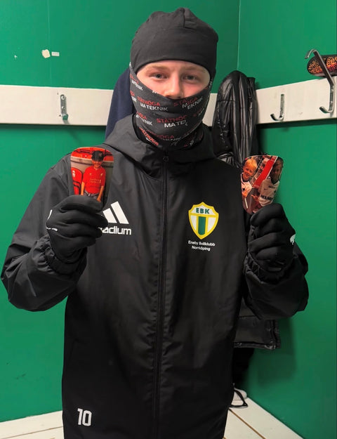 Fotbollsspelare i omklädningsrummet håller upp röda personliga benskydd med egna bilder